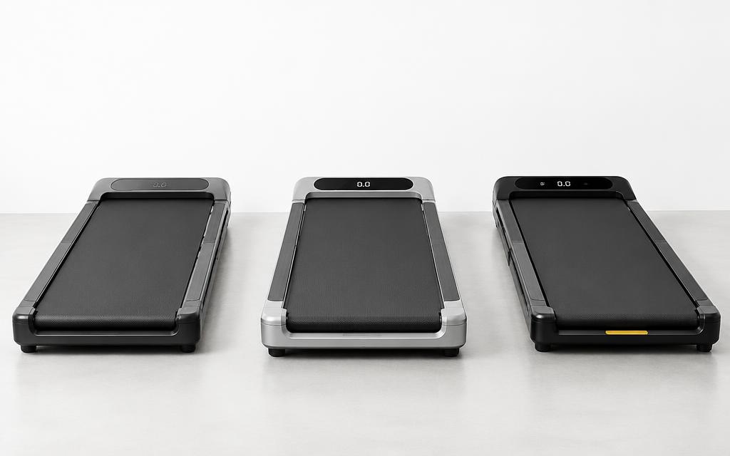 Three walking pads side by side on a light studio floor